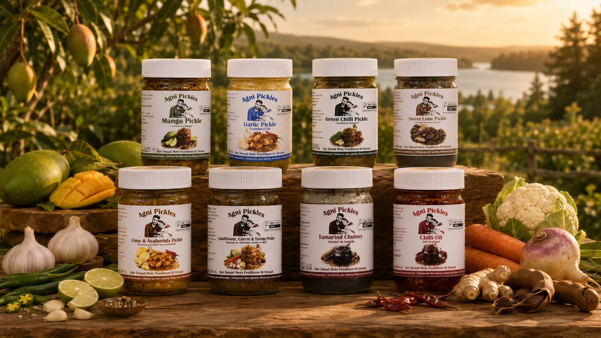 Eight jars of Nip's Pickles arranged on a wooden surface outdoors, with fresh vegetables and herbs around them and a scenic lake or forest background at sunset.