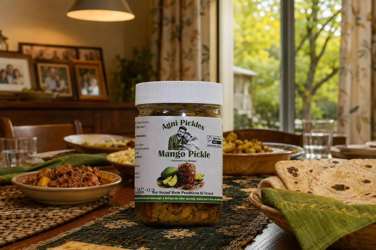 A jar of Agni Pickles Mango Pickle is prominently displayed on a dining table, surrounded by Indian food like flatbread, rice, and curries in a warm, home-style dining room setting.