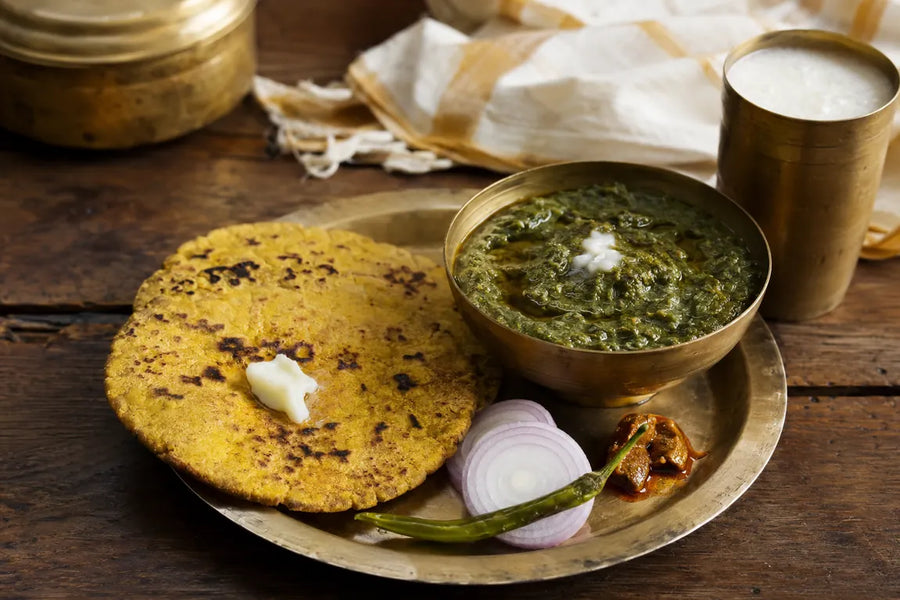 Traditional Punjabi meal of sarson da saag and makki di roti served with butter, onion, green chilli and pickle.