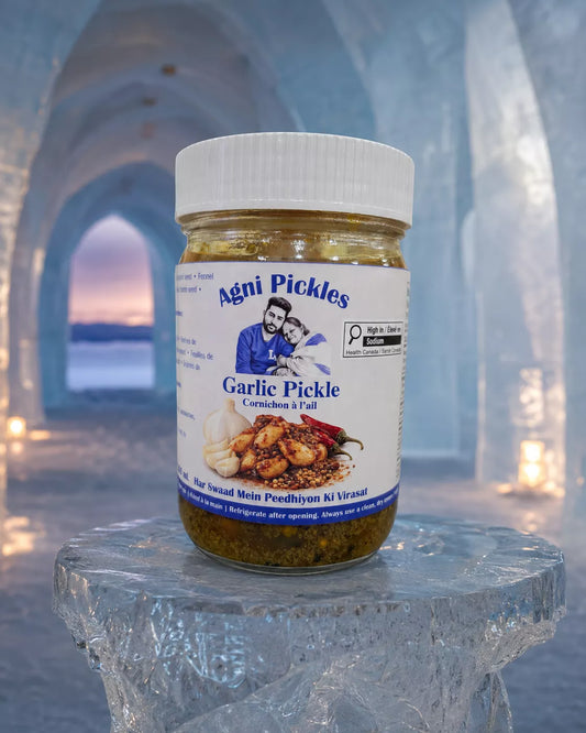 A jar of Agni Pickles Garlic Pickle (Cornichon & Fawl) placed on a clear ice pedestal, with a blurred icy cave background.