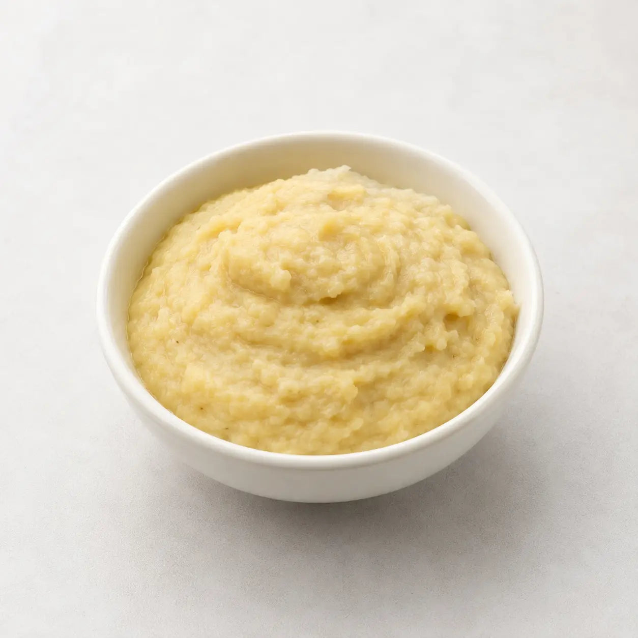 Fresh ginger-garlic paste served in a small white bowl on a light neutral background.