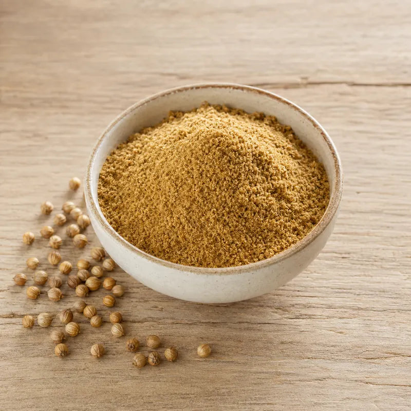 Ground coriander powder in a ceramic bowl with whole coriander seeds