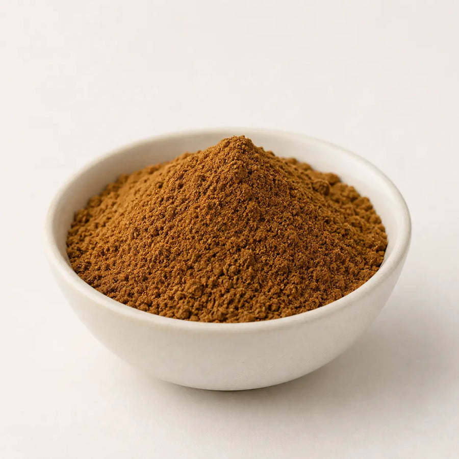 Roasted cumin powder in a small white bowl on a light neutral background.