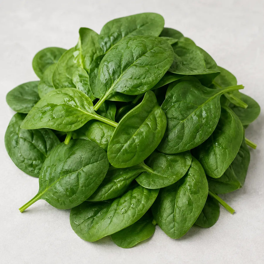 Fresh spinach leaves arranged in a pile on a light neutral background