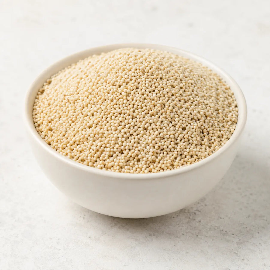 White poppy seeds piled in a small ceramic bowl on a clean light background.